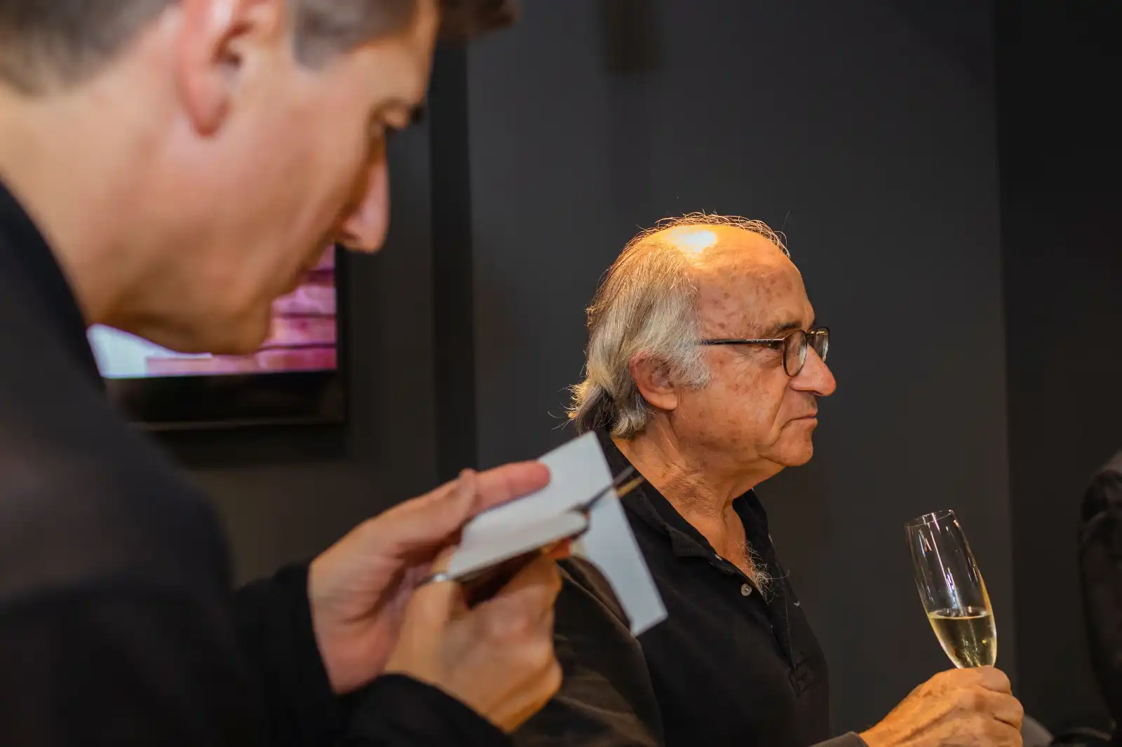 Un invité tenant une coupe de champagne pendant qu'Igor Kucinic découpe un portrait silhouette lors d'un cocktail
