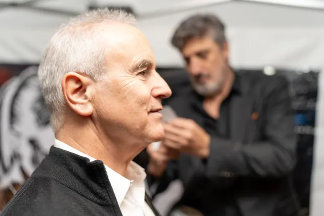 Un invité pose de profil pendant qu'Igor Kucinic découpe sa silhouette aux ciseaux, en direct